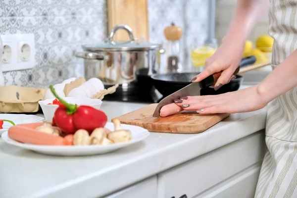 Крупним планом жіночі руки готують їжу на кухні, ріжуть ковбаски ножем — стокове фото