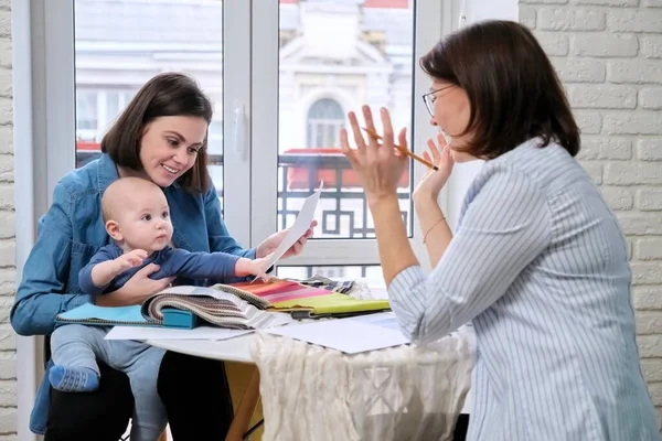 Mujer diseñadora de interiores y cliente con bebé eligiendo telas y materiales — Foto de Stock