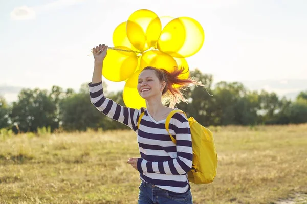 Feliz chica adolescente con globos corriendo y saltando a lo largo del camino del campo —  Fotos de Stock