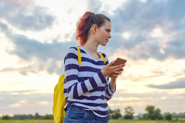 Chica adolescente con teléfono inteligente, cielo naturaleza pradera fondo — Foto de Stock