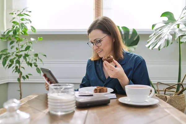 家で働く熟女の笑顔,朝食を持っているとデジタルタブレットを使用して,ビジネスノートブック — ストック写真