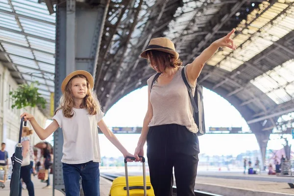 Счастливая мать и дочь ребенка ходить вместе на вокзале с чемоданом — стоковое фото