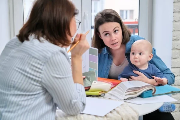 Women interior designer and client with baby choosing fabrics and materials