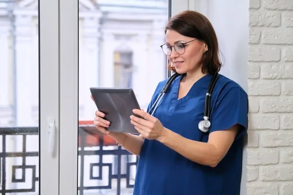 Female doctor talking online with patient using digital tablet, video call