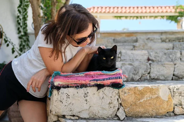 Happy woman with black cat, outdoor portrait of owner and pet