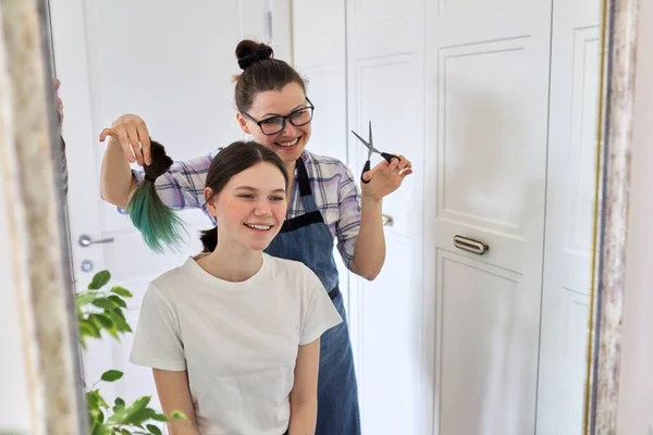 Corte de pelo en casa, mamá corta el pelo de las hijas, mujer corta el pelo teñido poco saludable —  Fotos de Stock