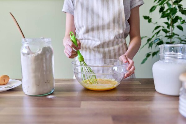 Процесс приготовления оранжевых блинов крупным планом, женские руки с миской
