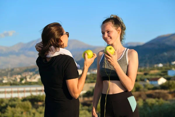 Gülümseyen fitness anne ve genç kız birlikte elma yiyorlar. — Stok fotoğraf