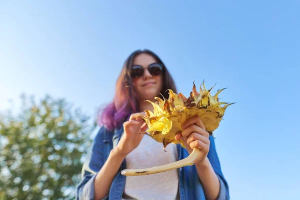 Dospívající dívka se zralou slunečnicovou rostlinou. Západ slunce, nebe pozadí, zdravý přírodní potravní koncept — Stock fotografie
