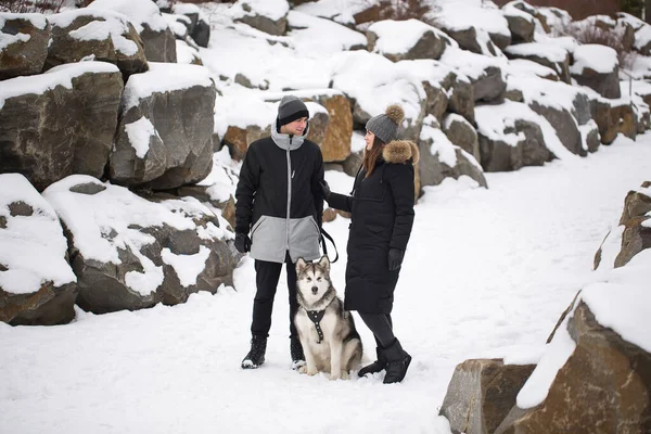 Bela família, um homem e uma menina na floresta de inverno com cão. Brincar com o cão Siberian husky . — Fotografia de Stock