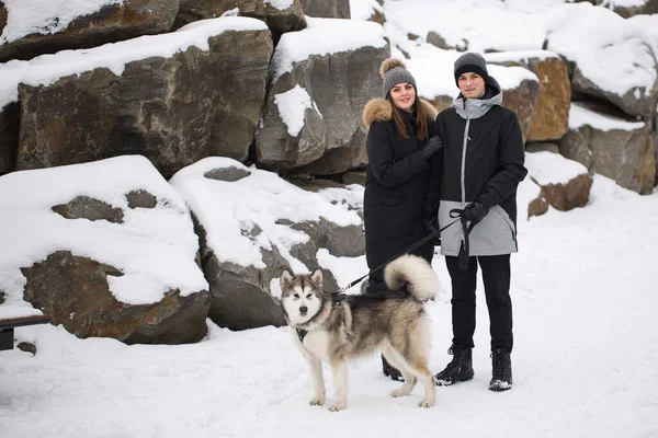 Bela família, um homem e uma menina na floresta de inverno com cão. Brincar com o cão Siberian husky . — Fotografia de Stock
