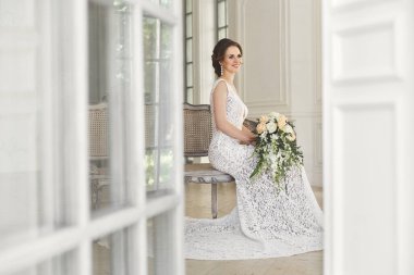 Güzel gelin gelinlik beyaz fotoğraf Studio poz. Ayna. Kanepe. Buket. Kapıyı. Avize.