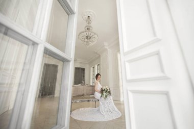 Güzel gelin gelinlik beyaz fotoğraf Studio poz. Ayna. Kanepe. Buket. Kapıyı. Avize.