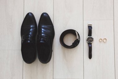 Düğün günü damat için aksesuarlar. Saatler, yüzükler, kemerler, ayakkabılar. Ahşap yüzey.