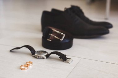 Düğün günü damat için aksesuarlar. Saatler, yüzükler, kemerler, ayakkabılar. Ahşap yüzey.