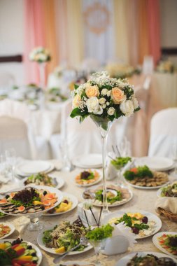 Restoranda masanın üstünde güzel çiçekler var. Düğün ziyafeti. Zarif bir yemek masası..