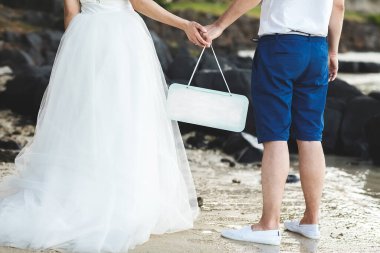 Gelin ve damat yazı için tabağı tebeşirle tutuyorlar. Okyanus. Plaj.