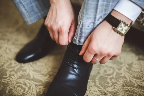 Sposo mettere le scarpe da sposa. Le mani di sposo nuziale che si prepara . — Foto Stock