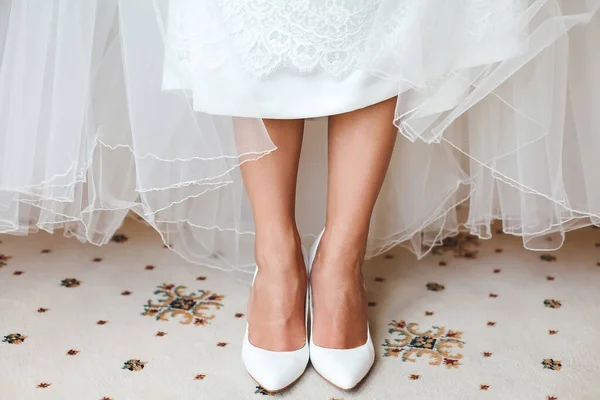 Novias pies en zapatos bajo vestido de novia . — Foto de Stock