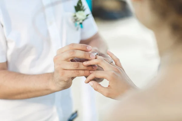 Noivo colocando um anel no dedo noivas durante a cerimônia de casamento . — Fotografia de Stock