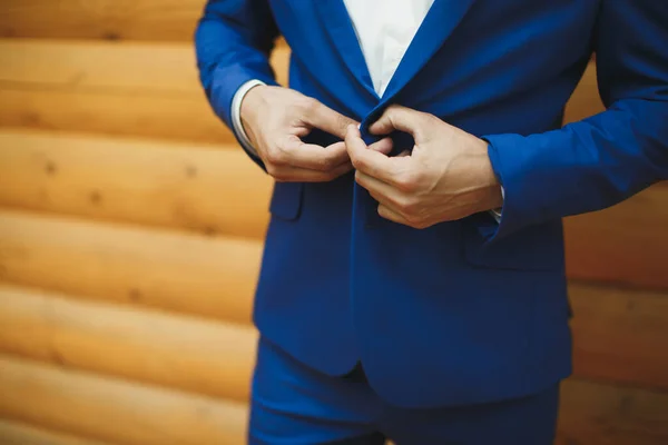 Man in the blue suit zips up the button on his jacket.