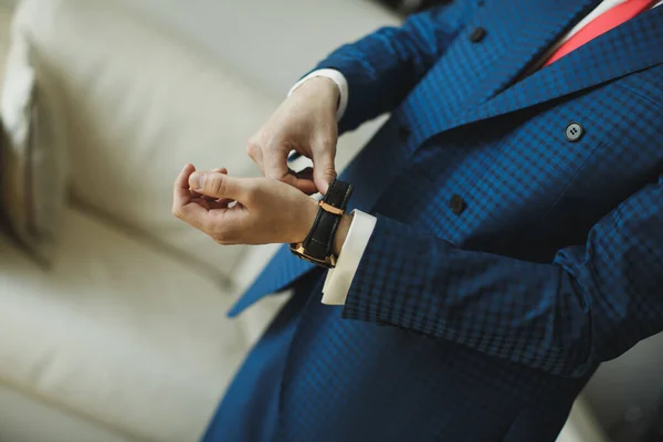 Un hombre de negocios con traje azul comprueba la hora con su reloj  . — Foto de Stock