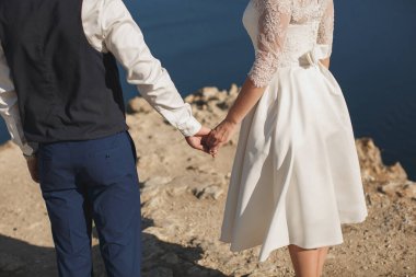 Gelin ve damat el ele yürüyorlar. Dağ. Deniz. Okyanus.