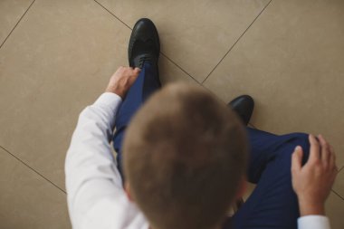 Erkek eli yeni ayakkabısının bağcıklarını bağlıyor. İnsanlar, iş, moda ve ayakkabı konsepti - insan bacağı ve ayakkabı bağlayan ellere yakın çekim.