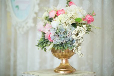 Güzel bir buket çiçek, altın bir vazoda, ahşap bir palette..