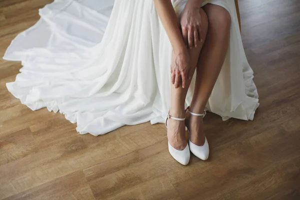 Bride puts on white shoes on feet. — Stock Photo, Image