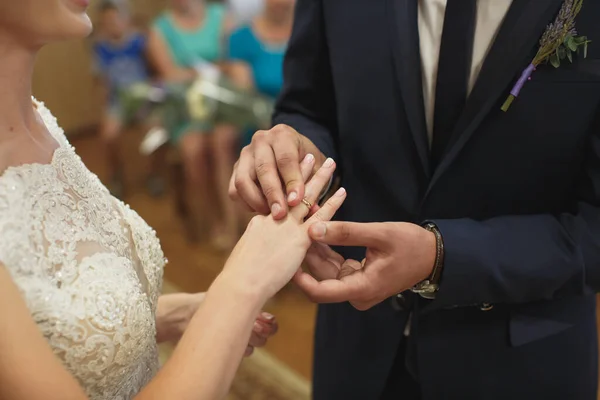 Новобрачные обмениваются кольцами, жених кладет кольцо на руки невесты в ЗАГС. — стоковое фото