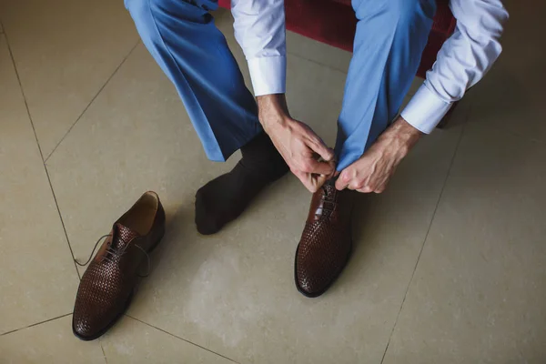 Le mani di Mans legano il lacci delle sue scarpe nuove. Concetto di uomo, business, moda e calzature - primo piano dei lacci uomo-gamba e mani . — Foto Stock