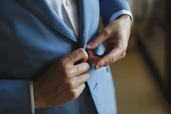 Man in the blue suit zips up the button on his jacket.