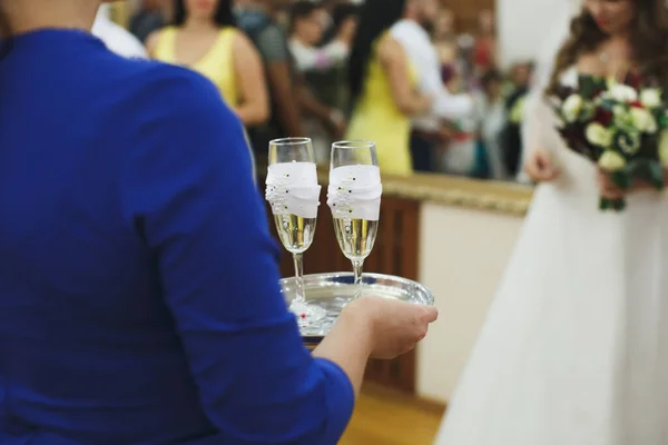 Novia y novio sosteniendo gafas de boda bellamente decoradas con champaign . — Foto de Stock