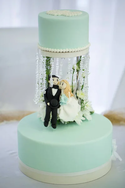 Wedding cake with crystals, flowers, and a figurine of the bride and groom.