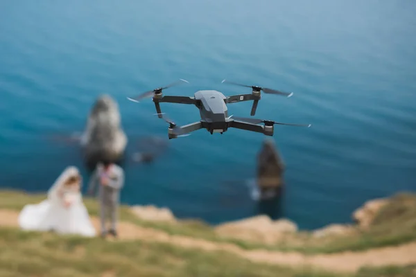 Bir drone, gelin ve damadın deniz kenarındaki bir uçurumda fotoğraflarını çeker..