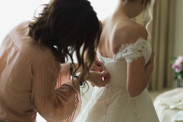 Dama de honor está ayudando a la novia a vestirse . —  Fotos de Stock