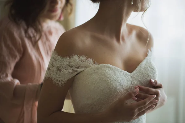 Подружка невесты помогает невесте одеться . — стоковое фото