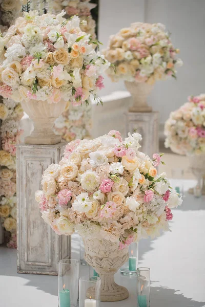 Bellissimo mazzo di rose in un vaso su uno sfondo di un arco nuziale. Bella allestita per la cerimonia nuziale . — Foto Stock