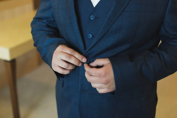 Närbild av händerna på brudgummen knäppning bröllop jackan. — Stockfoto