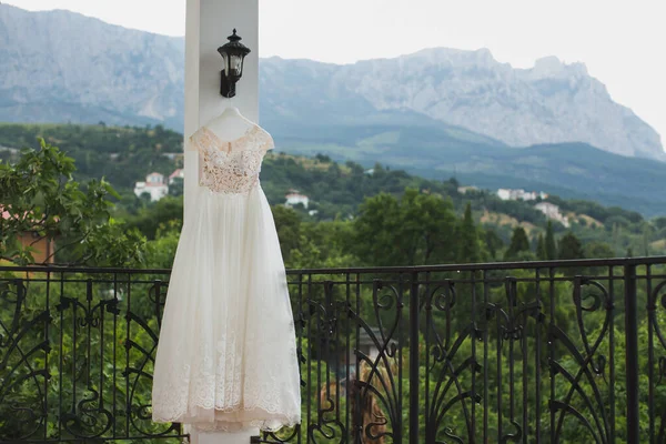 Свадебное платье висит на балконе на фоне заснеженных гор . — стоковое фото