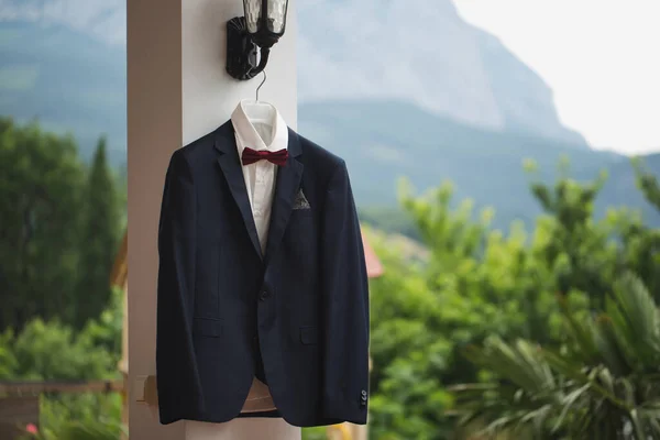 Groom suit jacket on a hanger mountain in the background.