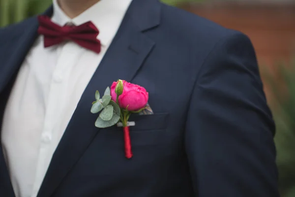 Piros rózsa boutonniere a vőlegény ruha. — Stock Fotó