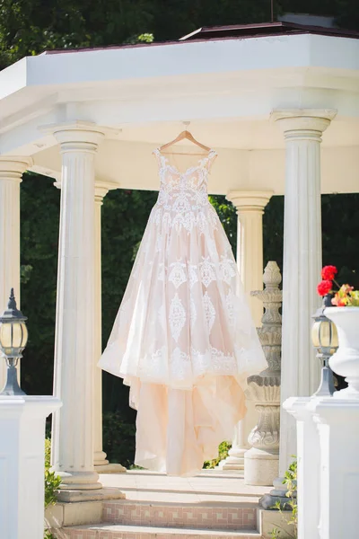 Bílé svatební šaty visí na ramínku. — Stock fotografie