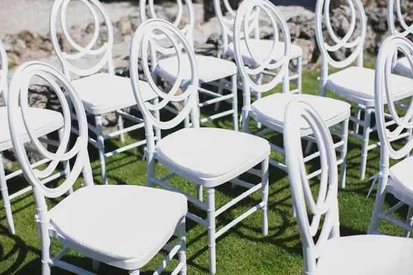 Chaise blanche décorant pour une cérémonie de mariage sur une pelouse verte . — Photo