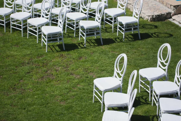 Chaise blanche décorant pour une cérémonie de mariage sur une pelouse verte . — Photo