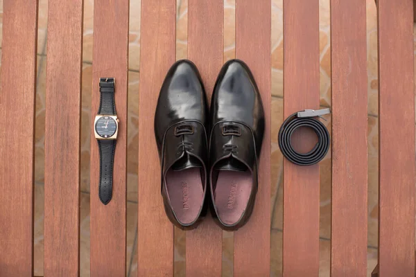 Classic men shoes, belt and watch on wooden boards.