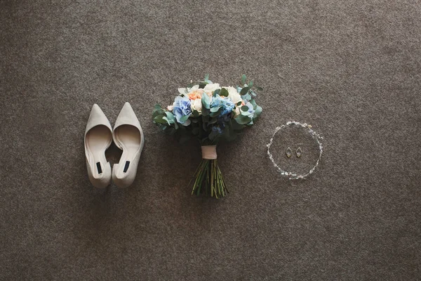 Tenera scarpe da sposa beige e orecchini e un bouquet da sposa . — Foto Stock