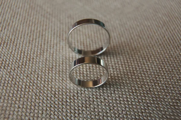 Krásné stříbrné snubní prsteny ležící na šedé tkanině. — Stock fotografie