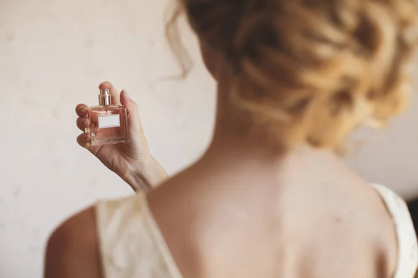 Una novia rubia en un vestido de novia disfruta del perfume . — Foto de Stock